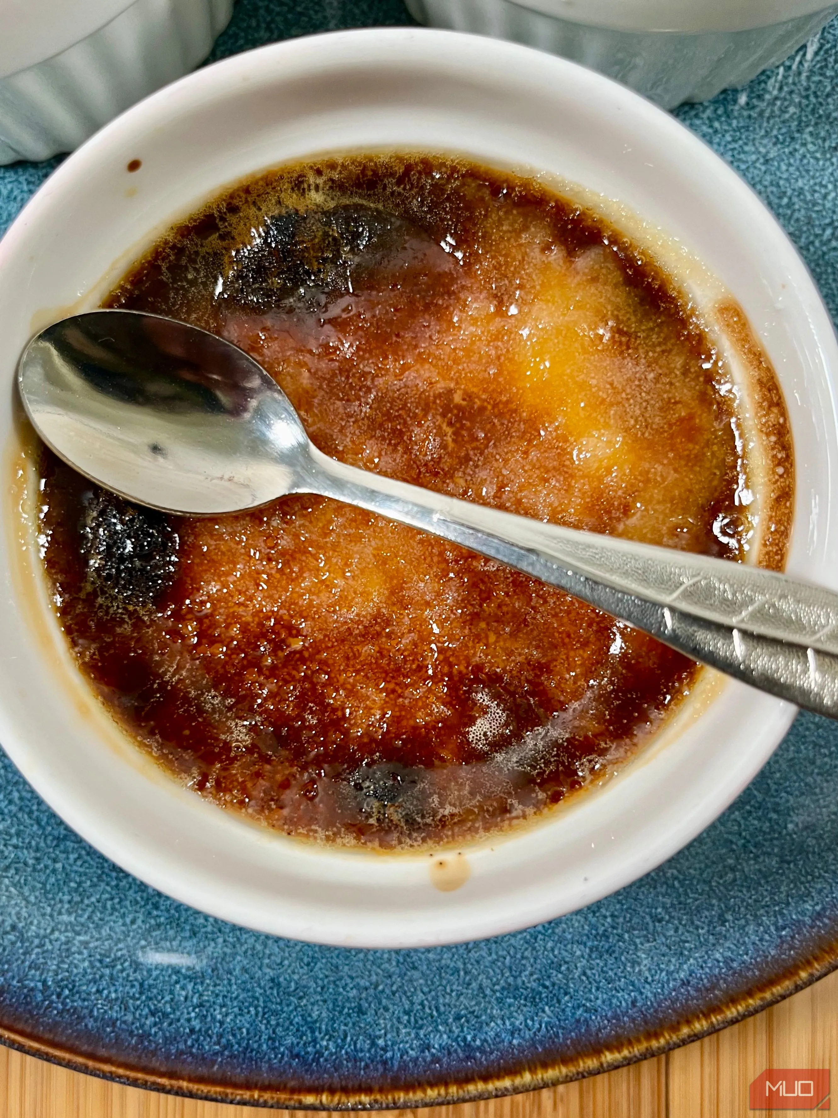 Ảnh chụp cận cảnh món kem cháy (Crème brûlée) trong bát sứ trắng, với bề mặt caramel vàng óng và ánh sáng mờ ảo, tạo không khí ấm cúng, cổ điển.