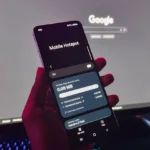 Bàn tay cầm điện thoại Android hiển thị cài đặt điểm phát sóng di động trước màn hình máy tính, minh họa việc tối ưu vị trí đặt hotspot.