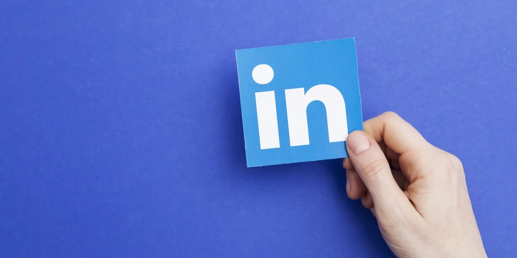 Bàn tay cầm logo LinkedIn, tượng trưng cho việc ứng dụng thu thập dữ liệu hồ sơ và thông tin hệ thống để đào tạo AI
