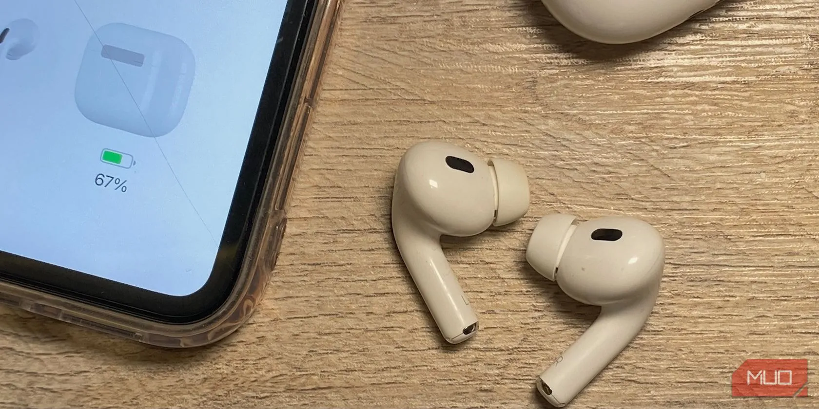 Các mẫu tai nghe AirPods nhét tai (AirPods và AirPods Pro) đặt trên bàn gỗ cạnh iPhone, cho thấy sự khác biệt về kích thước và thiết kế thân tai nghe.