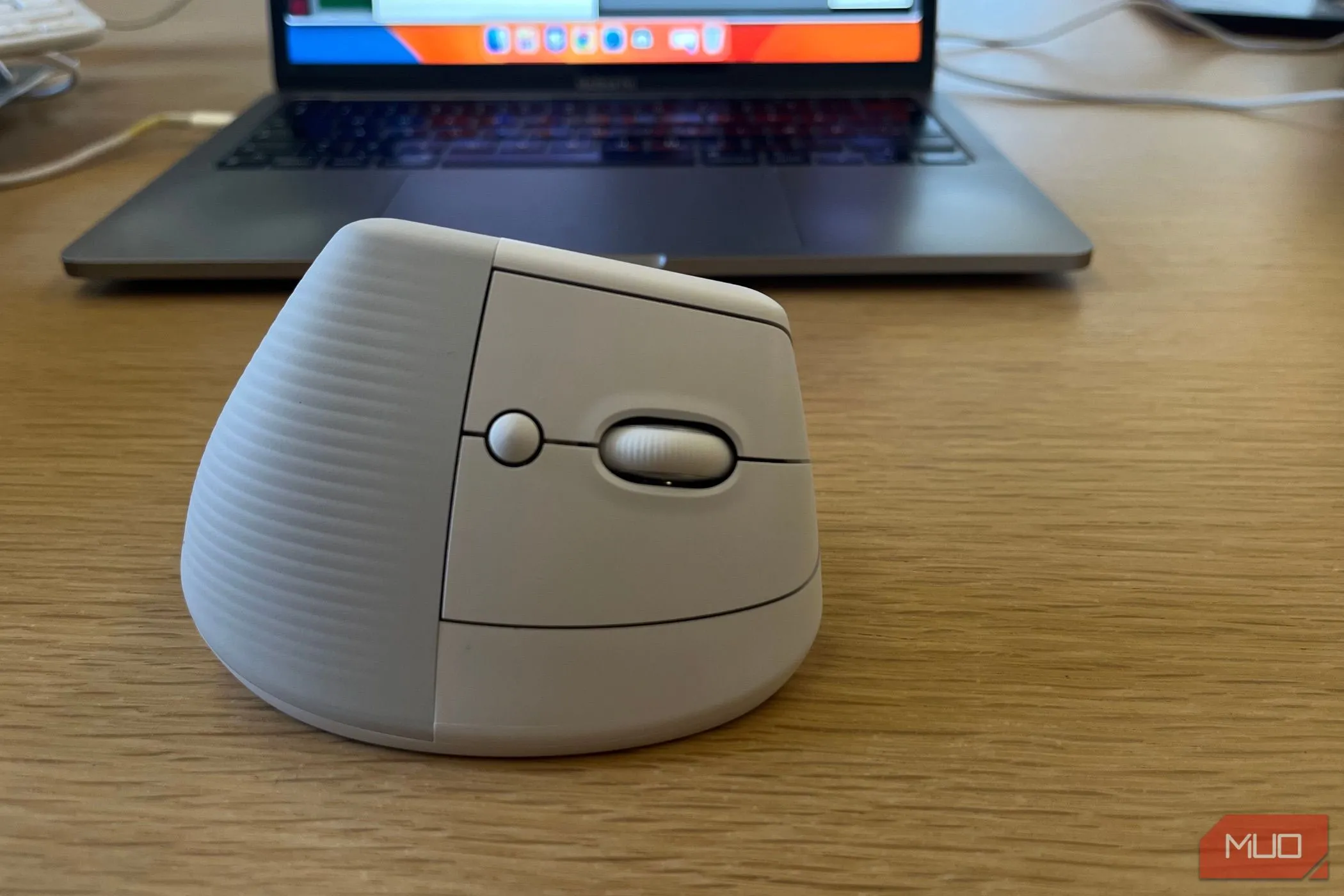 Chuột không dây Logitech Lift gần máy tính xách tay trên bàn làm việc, tối ưu ergonomics