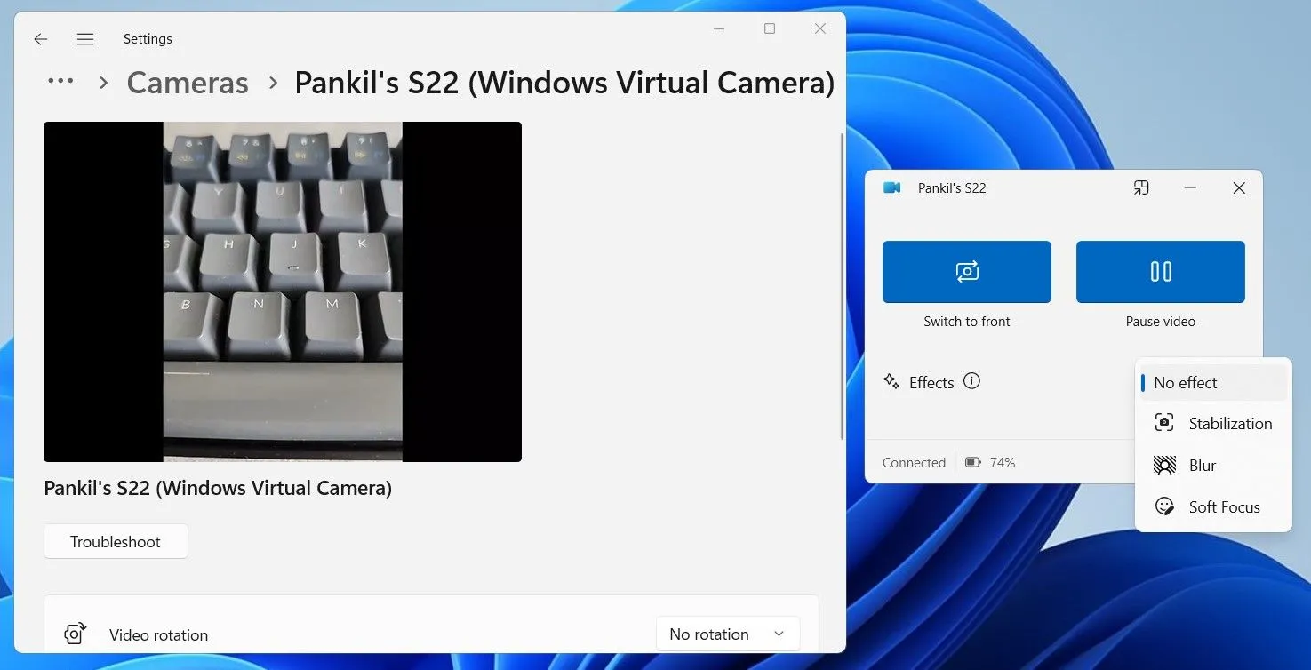 Điện thoại Android được đặt cạnh laptop, hiển thị màn hình video call, minh họa việc sử dụng điện thoại làm webcam cho máy tính chạy Windows 11 thông qua ứng dụng Phone Link