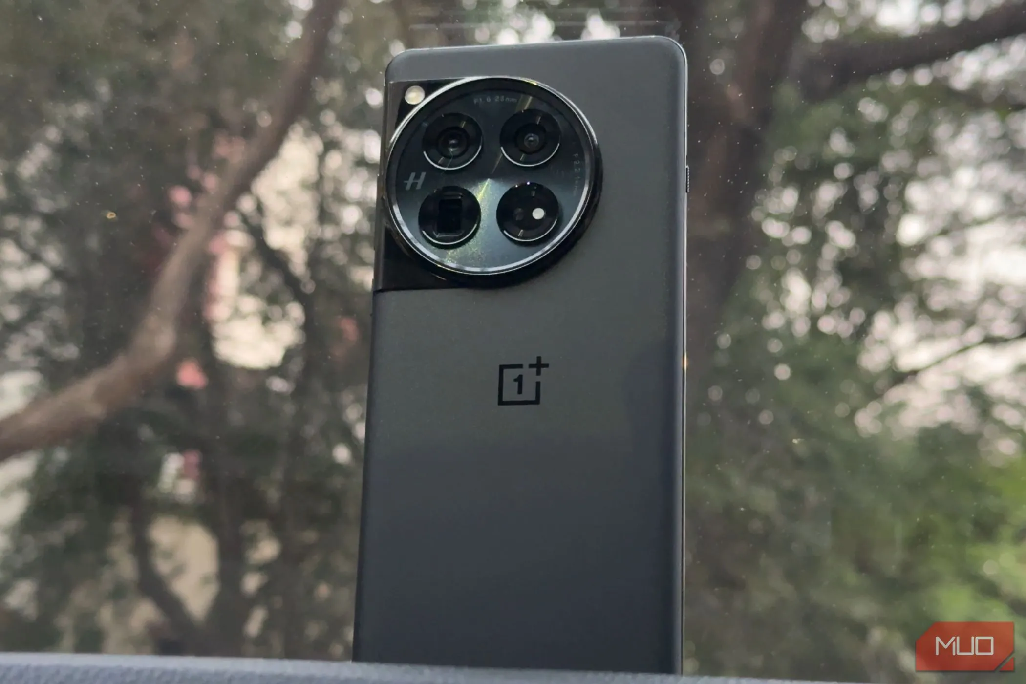 Điện thoại OnePlus 12 màu đen với mặt lưng độc đáo đặt trên bảng điều khiển xe ô tô