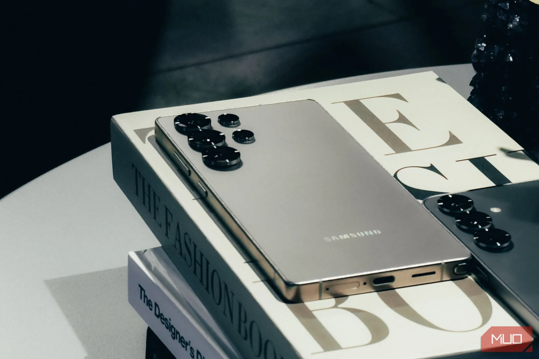 Điện thoại Samsung Galaxy S25 phiên bản Silver Shadow đặt nghiêng trên sách, nhấn mạnh thiết kế và khả năng sạc không dây Qi2