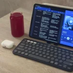 iPad Air M1, bàn phím Logitech Pebble Keys 2 K380s, tai nghe AirPods và cốc nước ép trên bàn làm việc