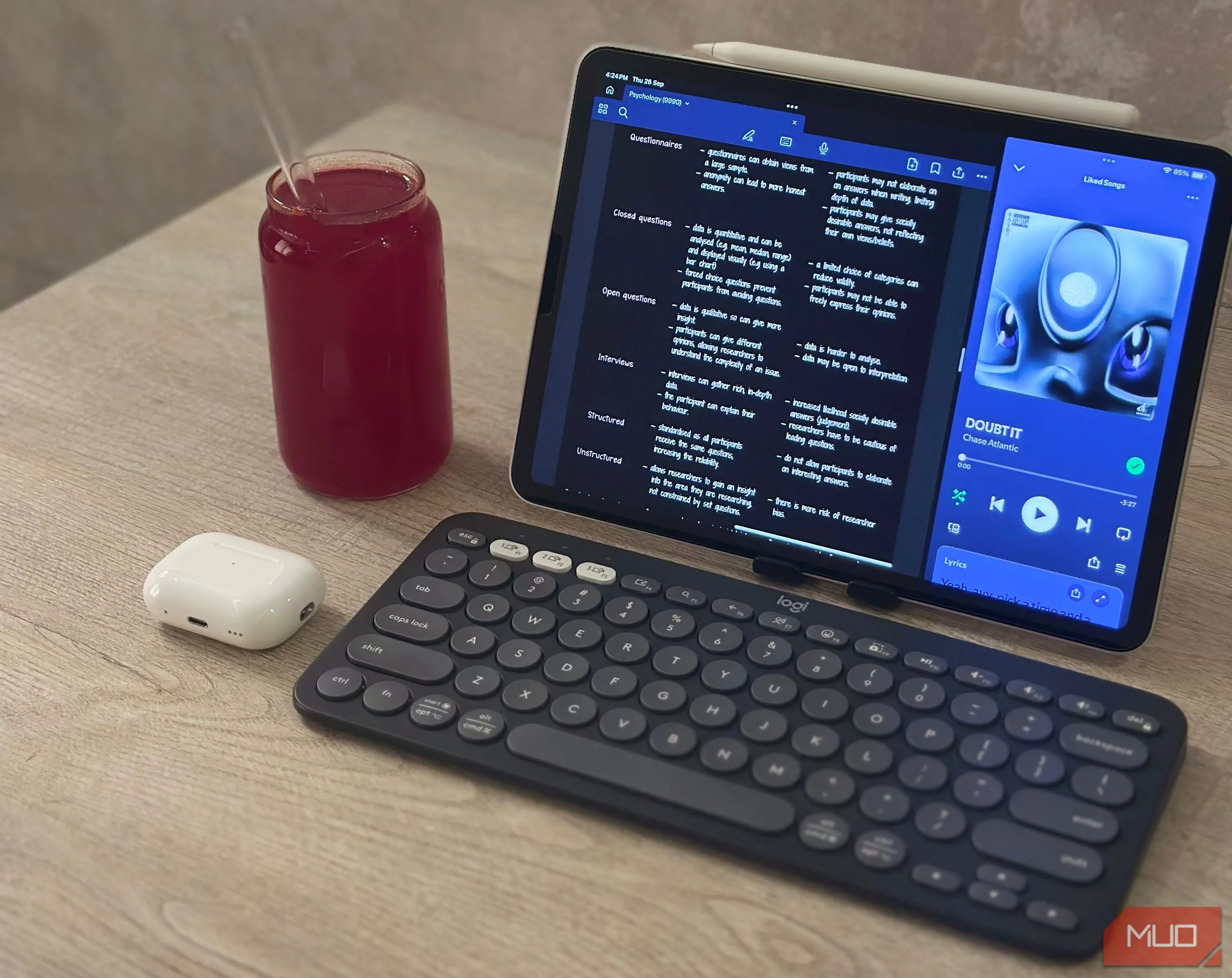iPad Air M1, bàn phím Logitech Pebble Keys 2 K380s, tai nghe AirPods và cốc nước ép trên bàn làm việc