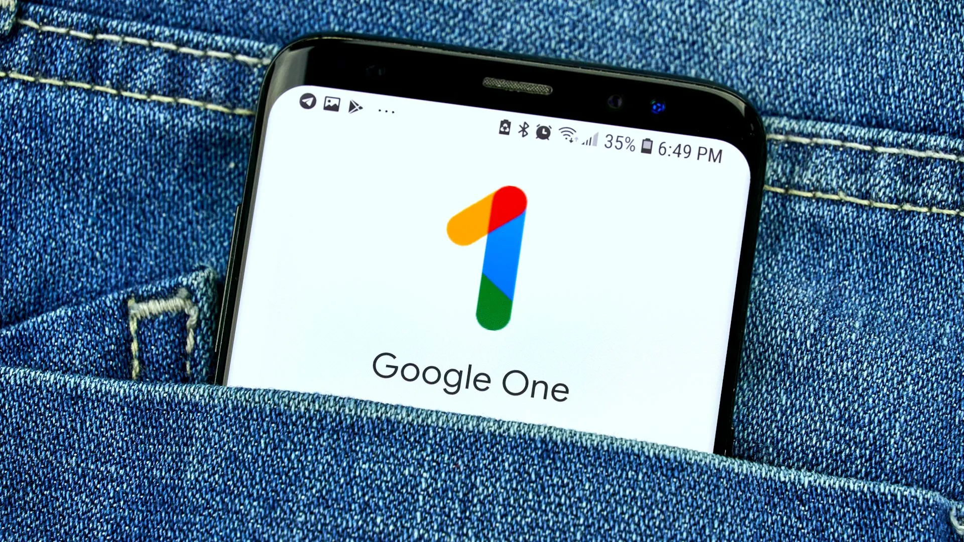 Màn hình điện thoại hiển thị ứng dụng Google One trong túi quần jean, minh họa việc truy cập dữ liệu đám mây