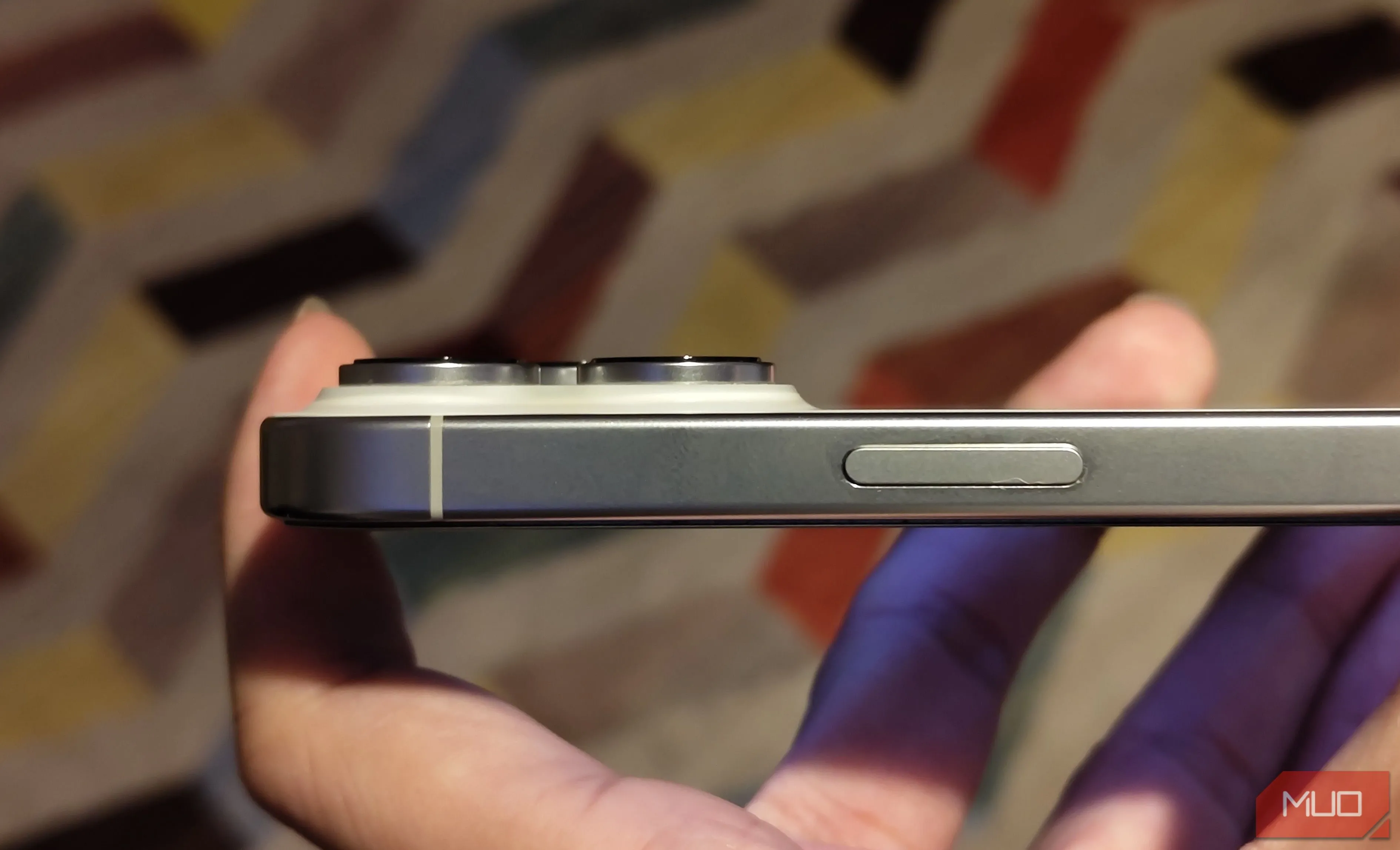 Mặt bên của một chiếc iPhone, cho thấy cụm camera lồi ra khỏi thân máy, minh họa thiết kế dễ bám bẩn.