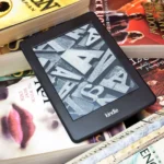 Máy đọc sách Kindle trên chồng sách vật lý, biểu tượng thư viện điện tử và sách in