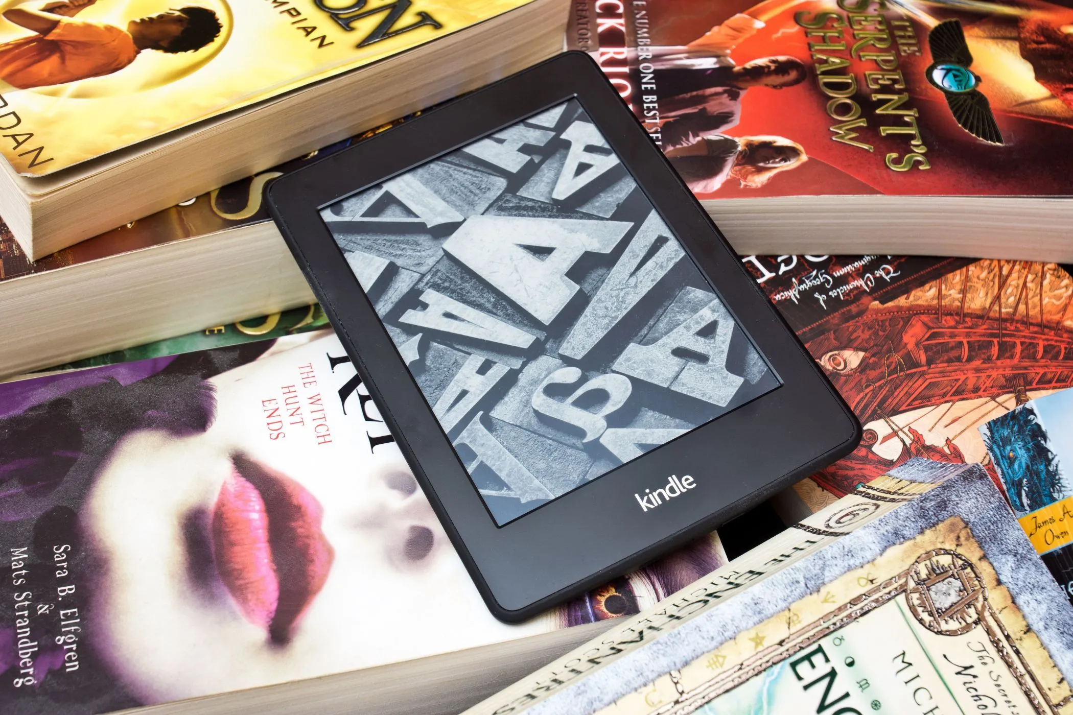 Máy đọc sách Kindle trên chồng sách vật lý, biểu tượng thư viện điện tử và sách in