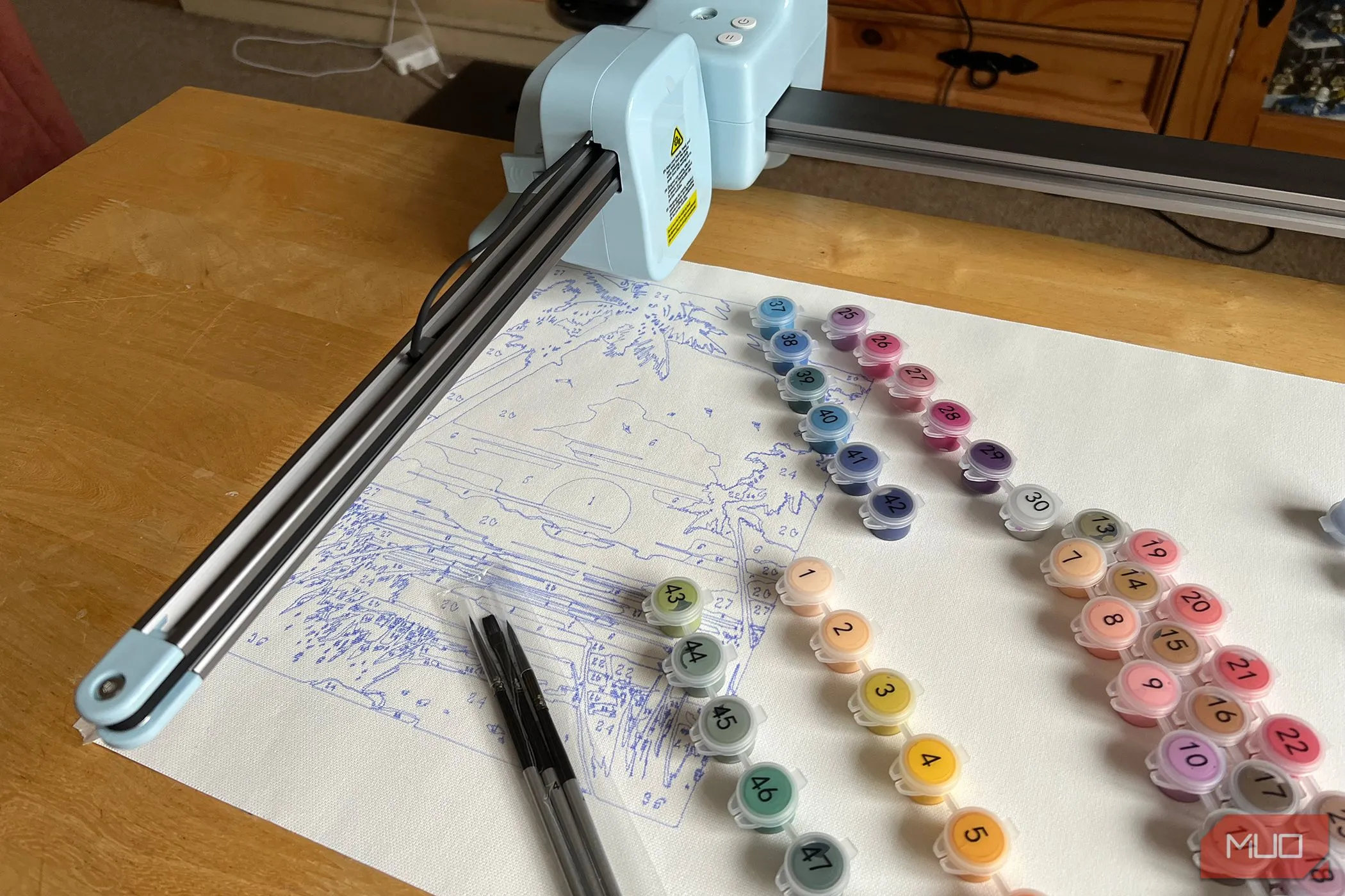 Máy LOKLiK iPaint đang vẽ một bức tranh hoàng hôn với các lọ sơn đi kèm