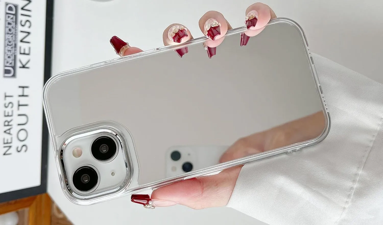 Một bàn tay đang cầm iPhone có ốp lưng gương phản chiếu