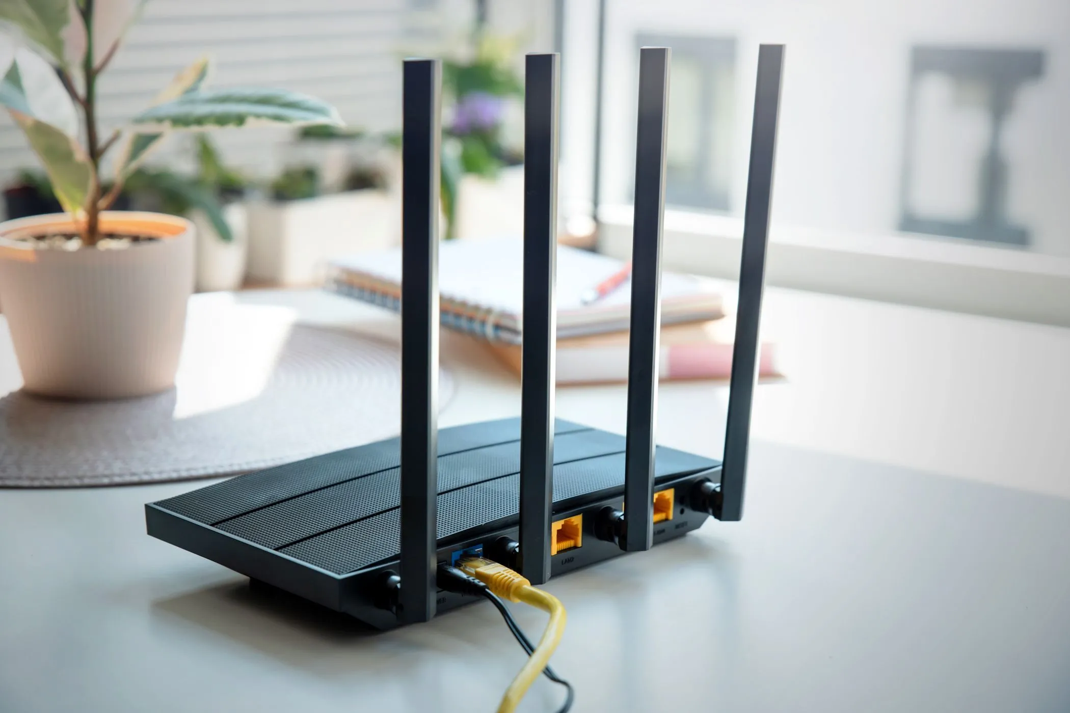 Một bộ định tuyến Wi-Fi (router) bốn ăng-ten hiện đại đặt trên bàn, minh họa cho việc sử dụng router phụ để tạo mạng khách.
