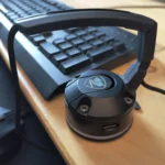 Một chiếc mouse bungee màu đen đang đặt trên bàn gỗ, giữ cho dây chuột gọn gàng và không vướng víu