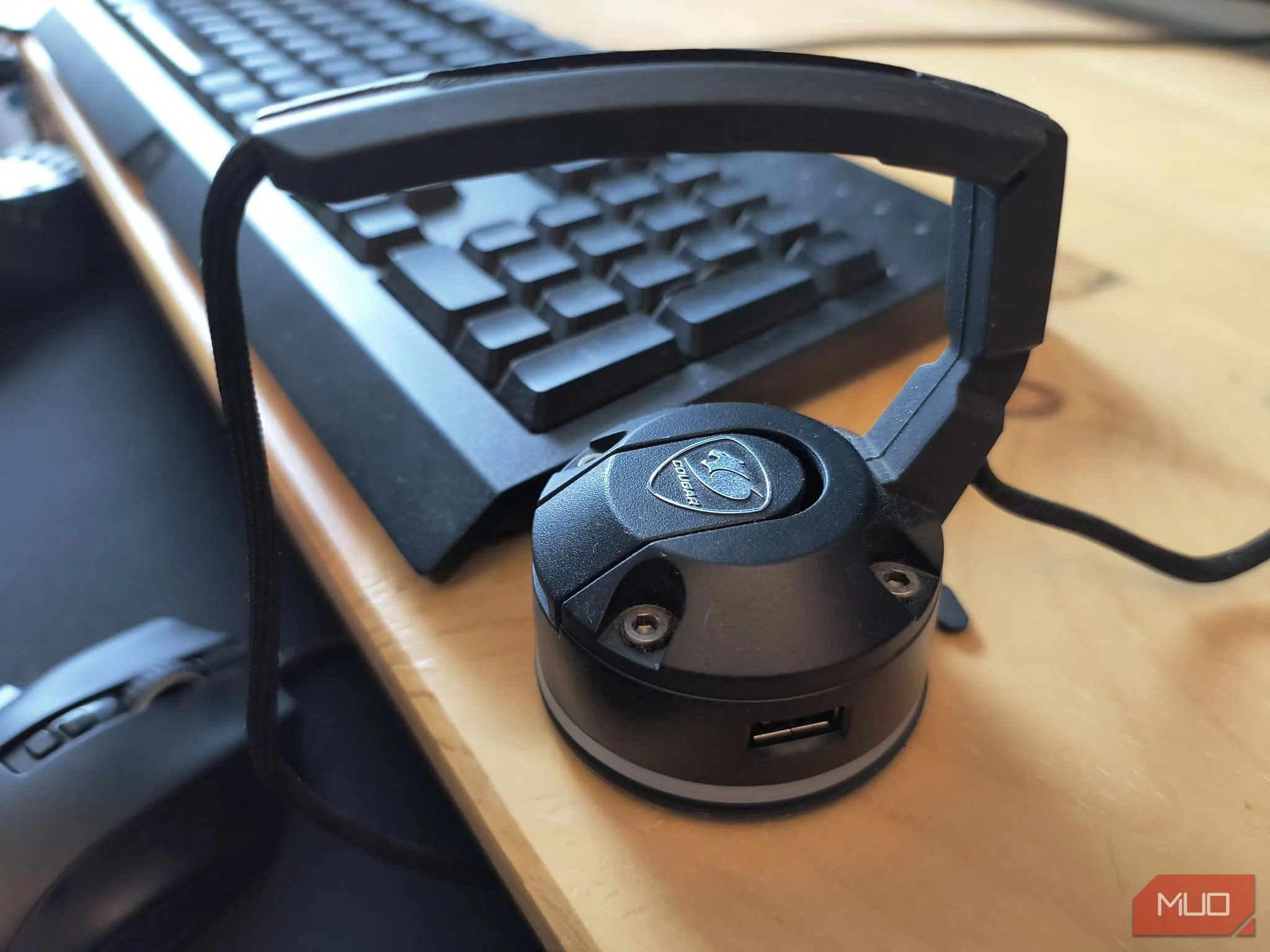 Một chiếc mouse bungee màu đen đang đặt trên bàn gỗ, giữ cho dây chuột gọn gàng và không vướng víu