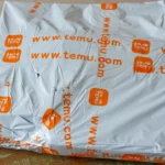 Một gói hàng Temu đặt trên bàn, tượng trưng cho việc mua sắm trực tuyến và vận chuyển hàng hóa quốc tế, trong bối cảnh Temu điều chỉnh giá do thuế quan tăng.