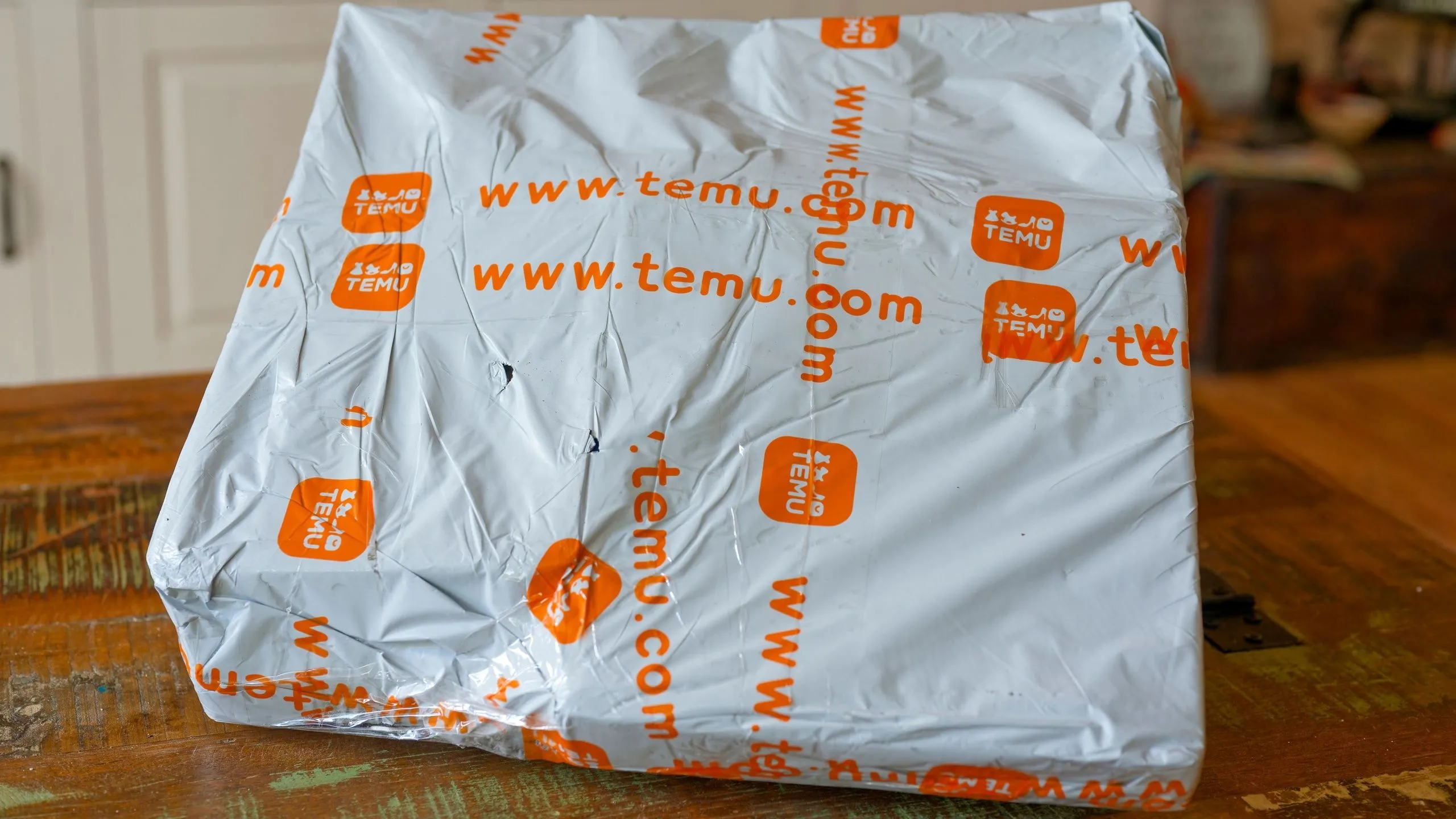Một gói hàng Temu đặt trên bàn, tượng trưng cho việc mua sắm trực tuyến và vận chuyển hàng hóa quốc tế, trong bối cảnh Temu điều chỉnh giá do thuế quan tăng.
