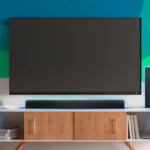 Một hệ thống TV treo tường và soundbar đặt trên kệ, minh họa thiết lập giải trí gia đình phổ biến nơi cài đặt Bitstream thường mang lại hiệu quả âm thanh tốt nhất.