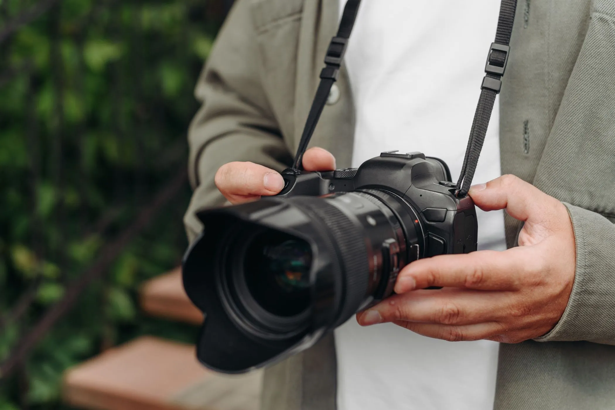 Một nhiếp ảnh gia trẻ tuổi cầm máy ảnh DSLR chắc chắn trên tay, tượng trưng cho độ bền và khả năng chịu đựng của thiết bị.