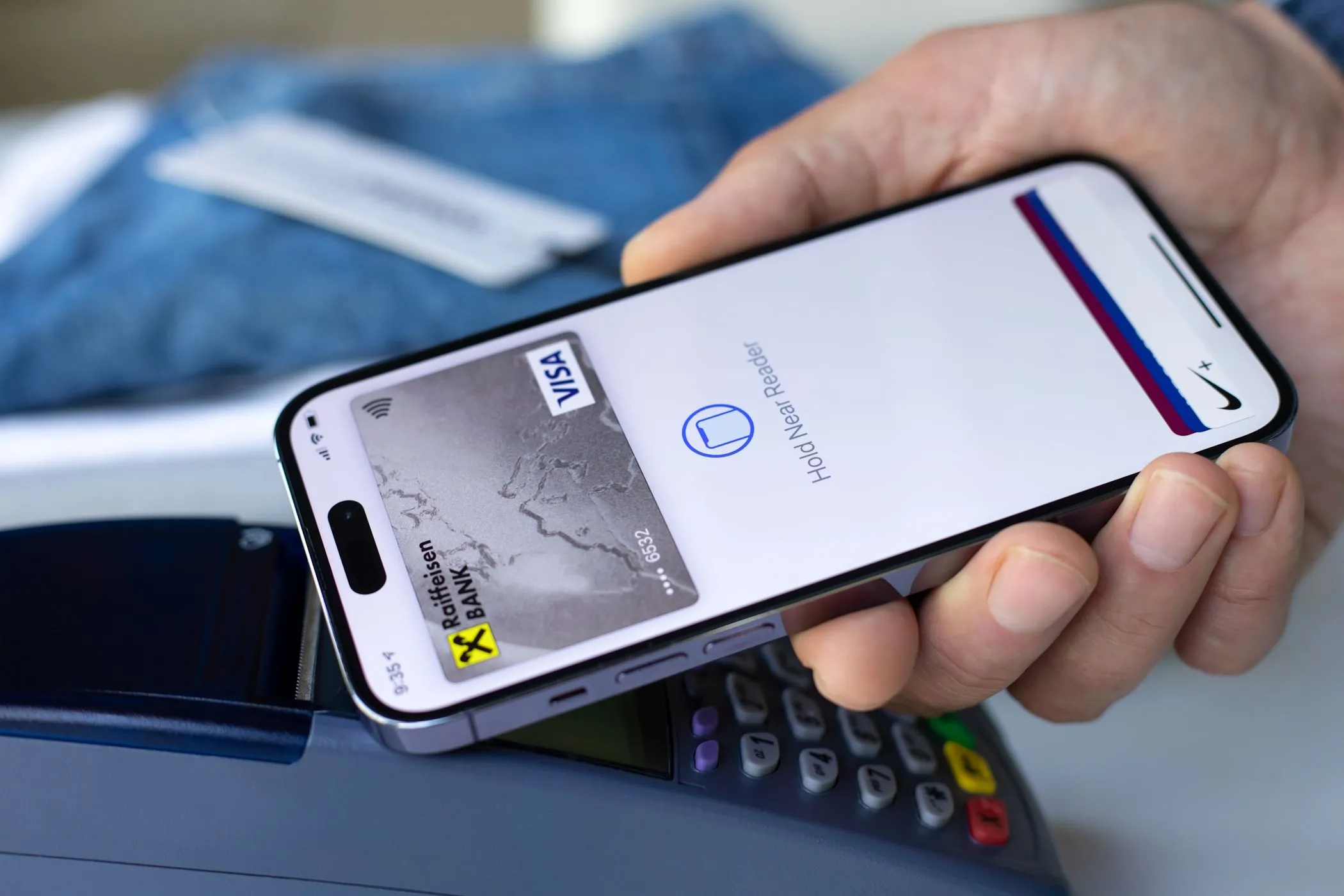 Người đàn ông thanh toán không tiền mặt bằng điện thoại iPhone tại quầy thu ngân, thể hiện sự tiện lợi của giao dịch kỹ thuật số và mối liên hệ với dữ liệu khách hàng thân thiết.