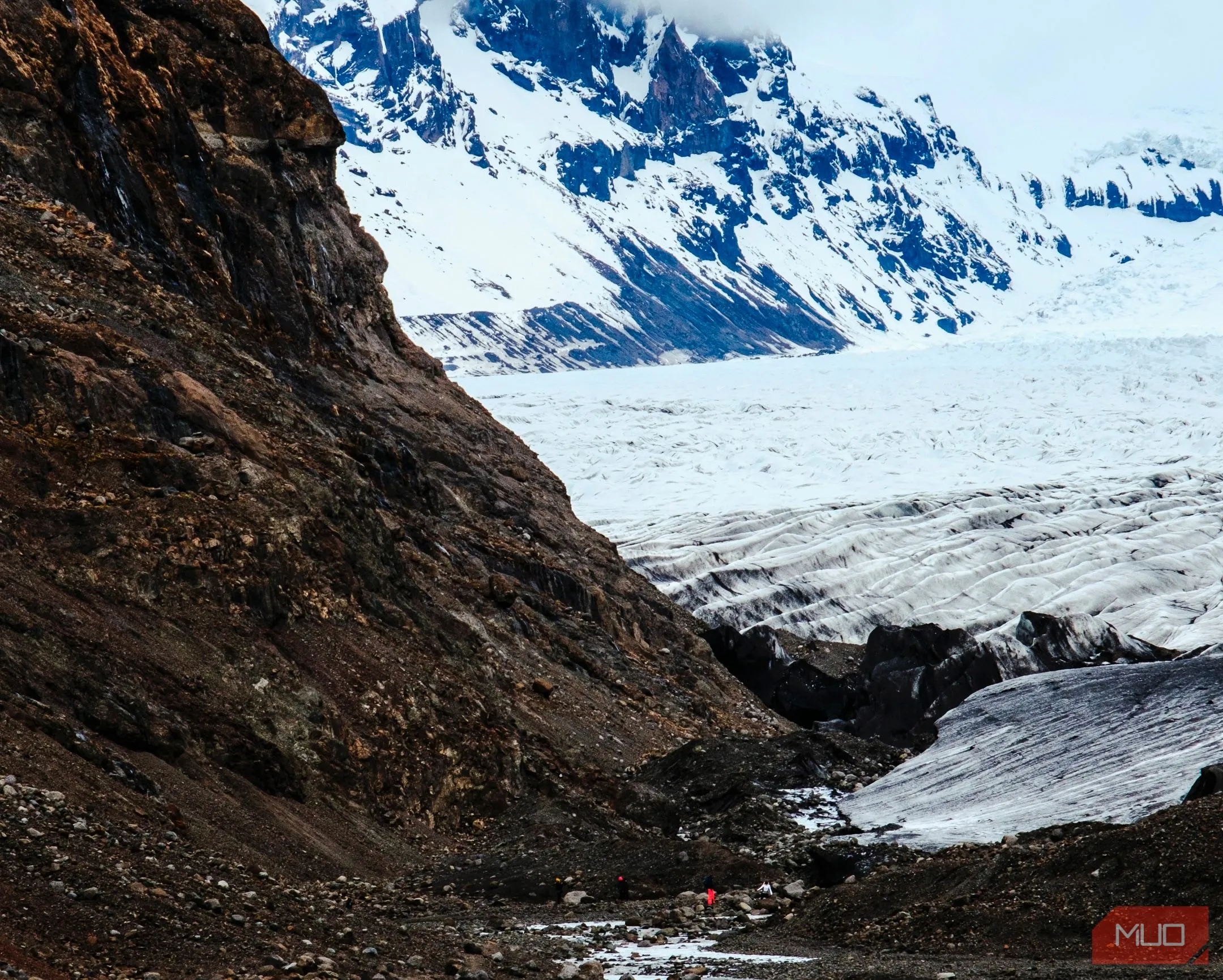 Người đang đi bộ giữa sông băng và núi non hùng vĩ tại công viên quốc gia Iceland, minh họa khả năng zoom và chi tiết của DSLR.