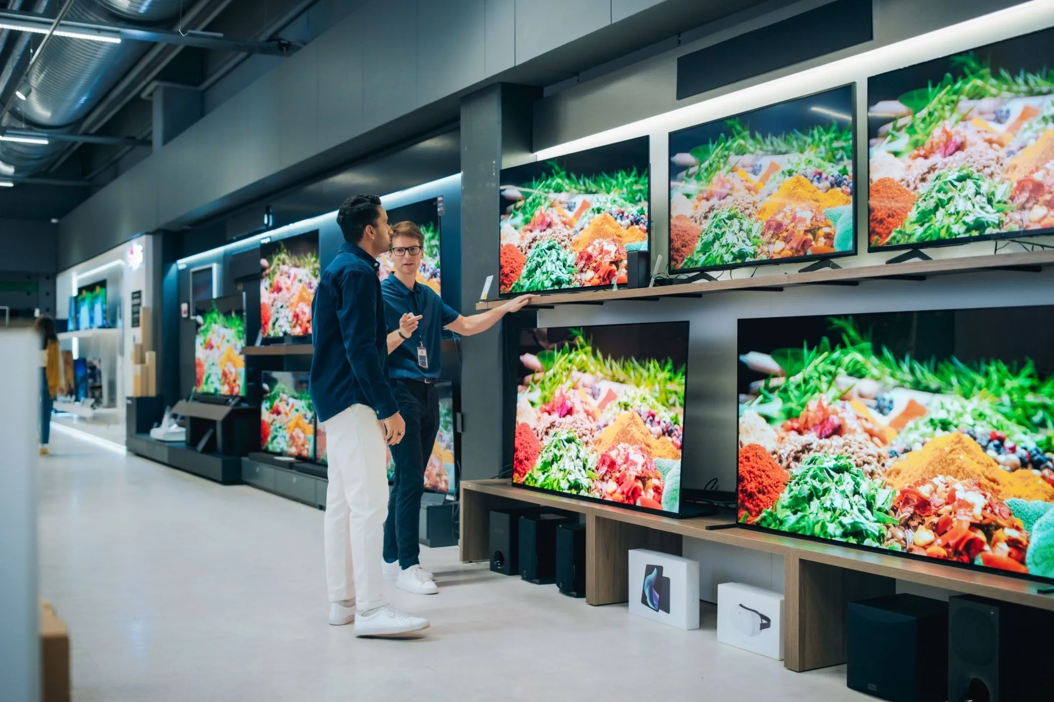 Nhân viên cửa hàng tư vấn sản phẩm TV cho khách hàng, minh họa trải nghiệm mua sắm cá nhân hóa và các ưu đãi dành cho thành viên thân thiết.