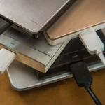 Nhiều ổ cứng di động và ổ đĩa ngoài đặt trên laptop minh họa sự phức tạp của việc quản lý lưu trữ khi phân vùng ổ cứng