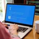 Phụ nữ đang xem màn hình xanh chết chóc (BSOD) trên laptop, minh họa lỗi hệ điều hành Windows nghiêm trọng cần USB Live Linux cứu hộ.