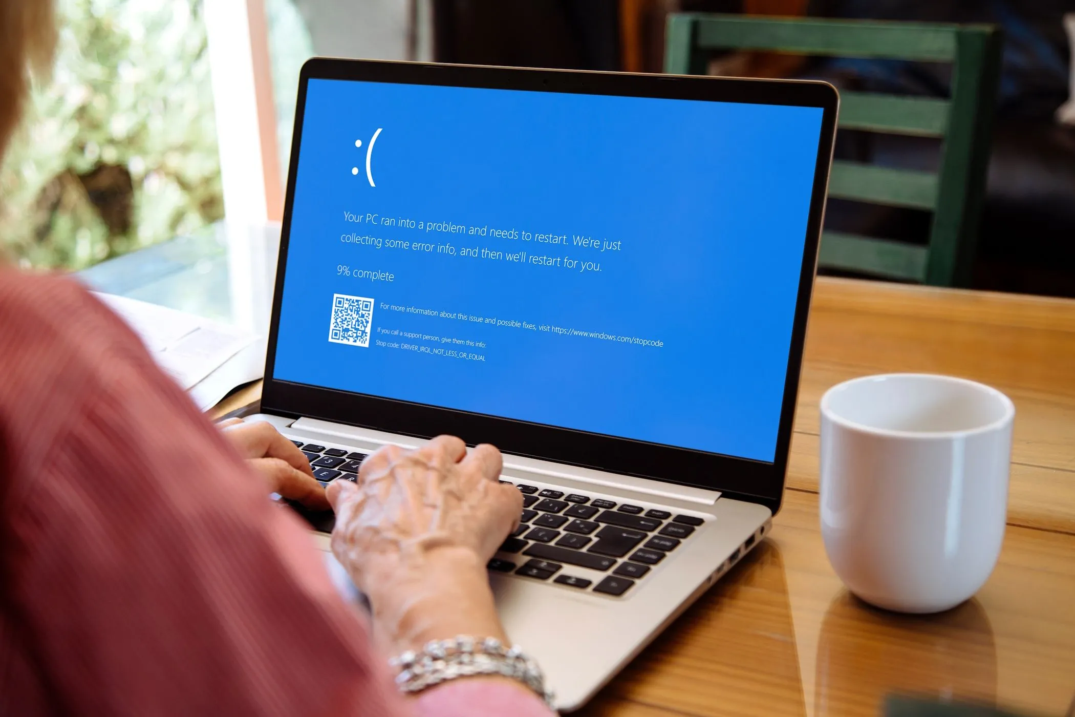 Phụ nữ đang xem màn hình xanh chết chóc (BSOD) trên laptop, minh họa lỗi hệ điều hành Windows nghiêm trọng cần USB Live Linux cứu hộ.