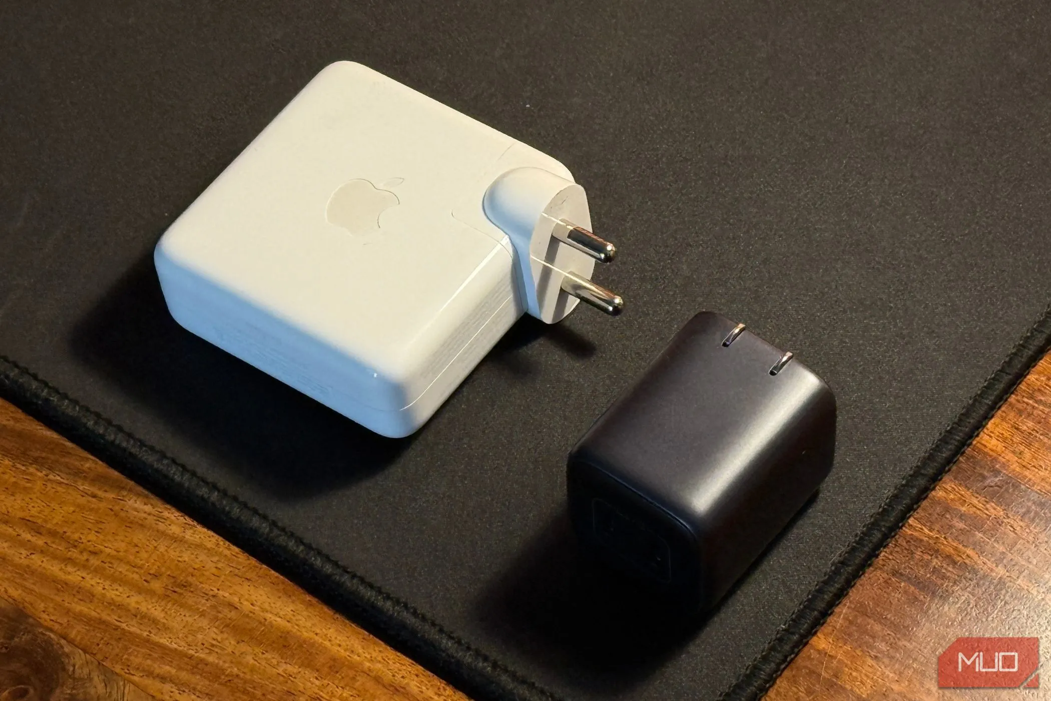So sánh kích thước giữa bộ sạc iPhone nhỏ gọn và bộ sạc MacBook lớn hơn, minh họa sự đa dạng về công suất và thiết kế.