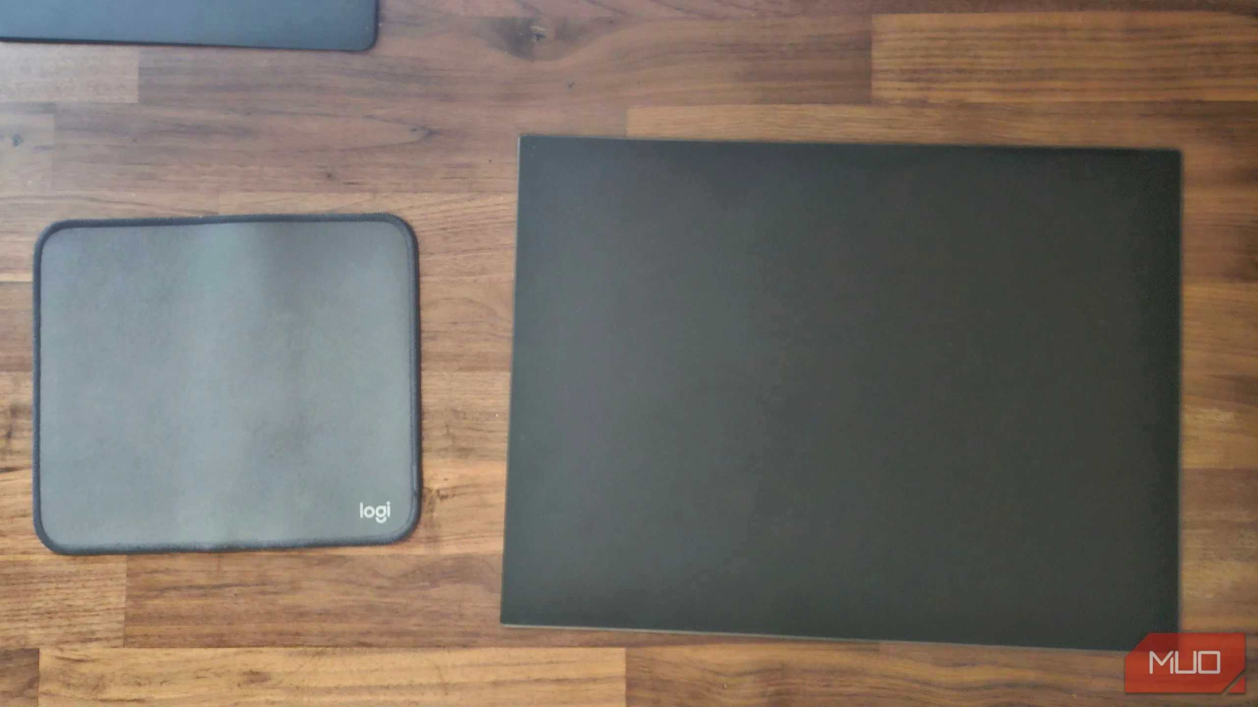 So sánh tấm lót chuột Logitech bằng vải truyền thống và tấm lót chuột kính cường lực, làm nổi bật vẻ ngoài cao cấp và khác biệt.