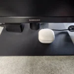 Tai nghe Bluetooth đang sạc pin qua cổng USB trên màn hình máy tính.