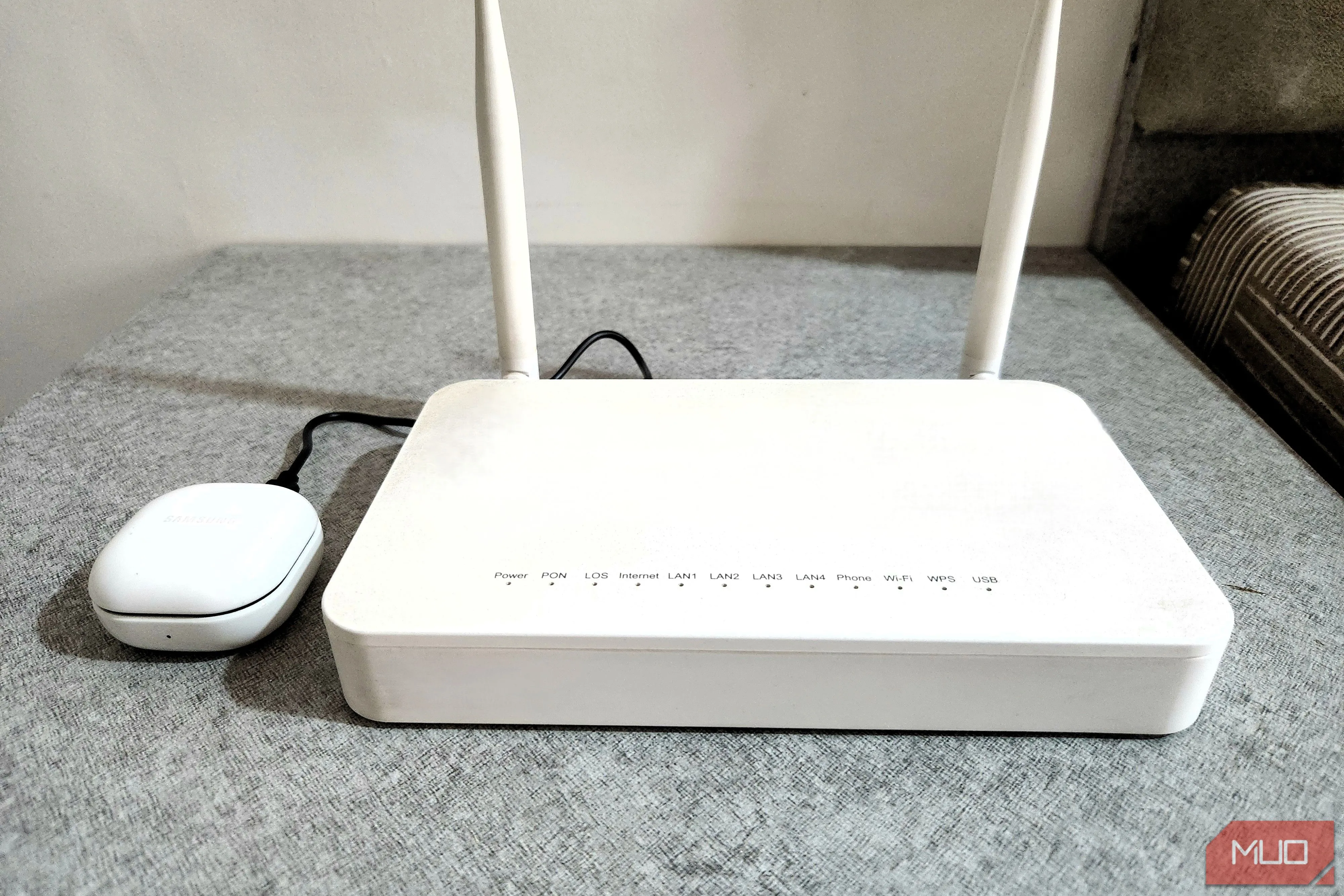 Tai nghe Bluetooth đang sạc qua cổng USB của router, minh họa khả năng cấp nguồn cho các thiết bị công suất thấp.
