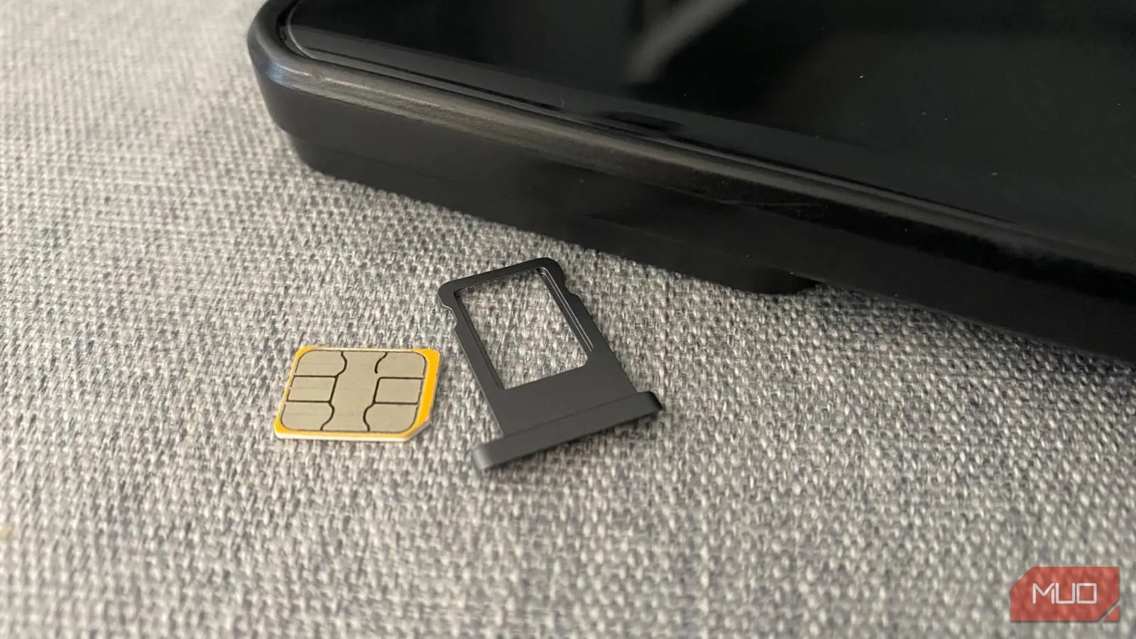 Thẻ SIM vật lý và khe cắm SIM đặt cạnh điện thoại di động, biểu tượng cho việc sử dụng SIM truyền thống.