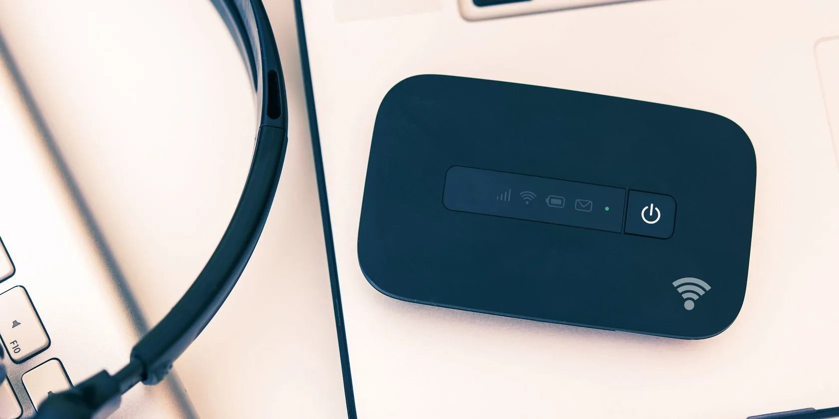 Thiết bị phát Wi-Fi di động đặt cạnh laptop, giải pháp internet riêng tư và ổn định cho người làm việc tại quán cà phê.