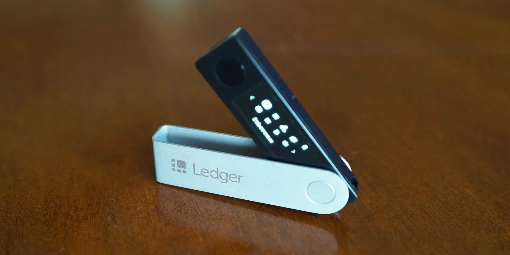 Thiết bị ví lạnh Ledger Nano X màu đen đặt trên bề mặt gỗ, tượng trưng cho bảo mật tài sản tiền điện tử.