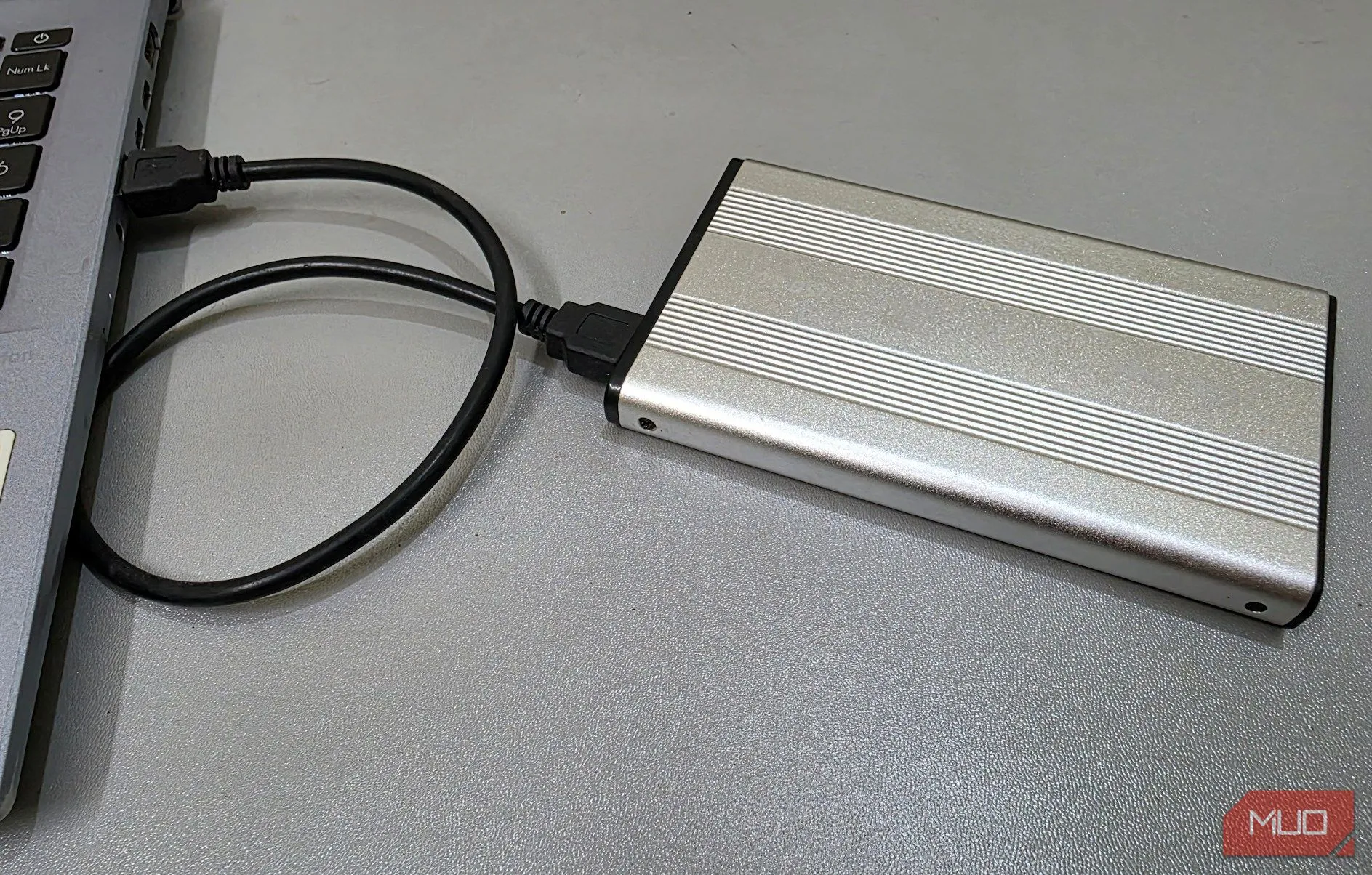 Vỏ bọc ổ cứng ngoài được kết nối với laptop, tượng trưng cho việc sử dụng ổ cứng cũ làm kho lưu trữ dữ liệu nhạy cảm được mã hóa.